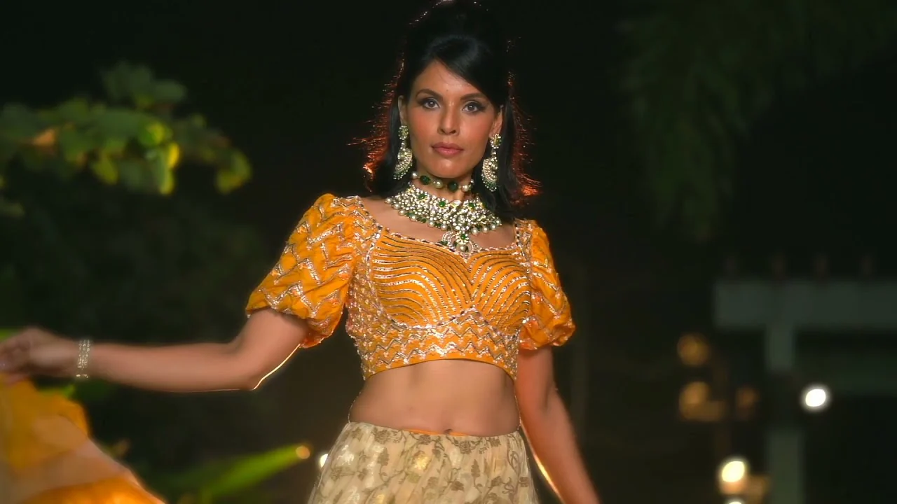 Model in an orange lehenga on the night runway
