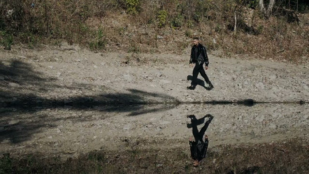 Figure walking, mirrored in the water