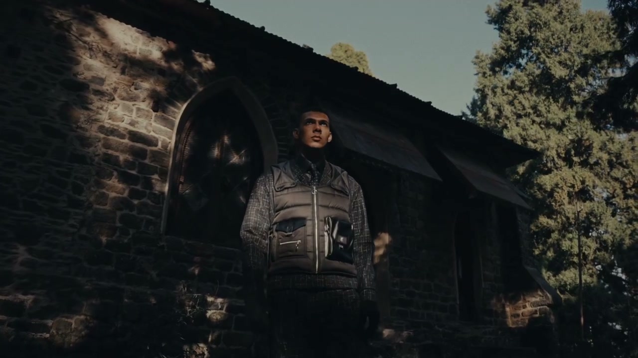 Model in a grey jacket against the stone chapel