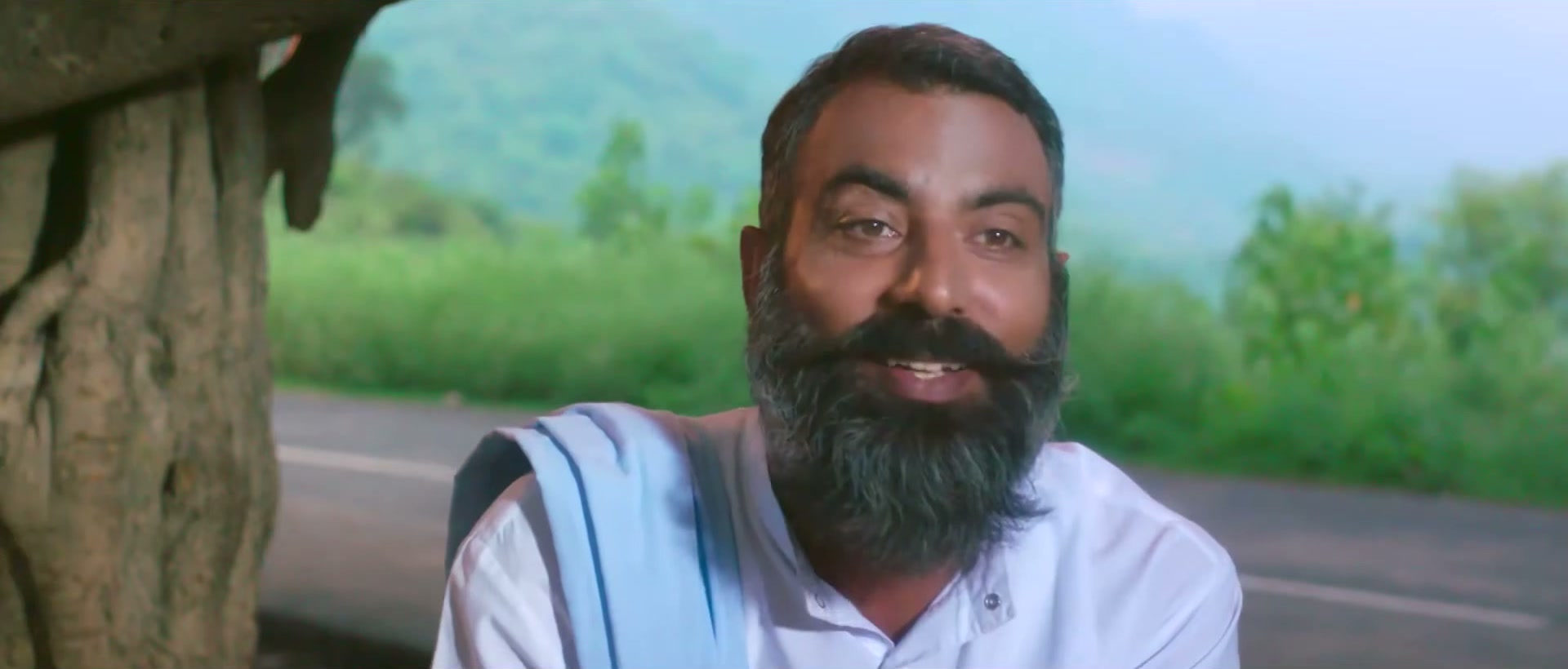 Bearded farmer smiling, hills behind